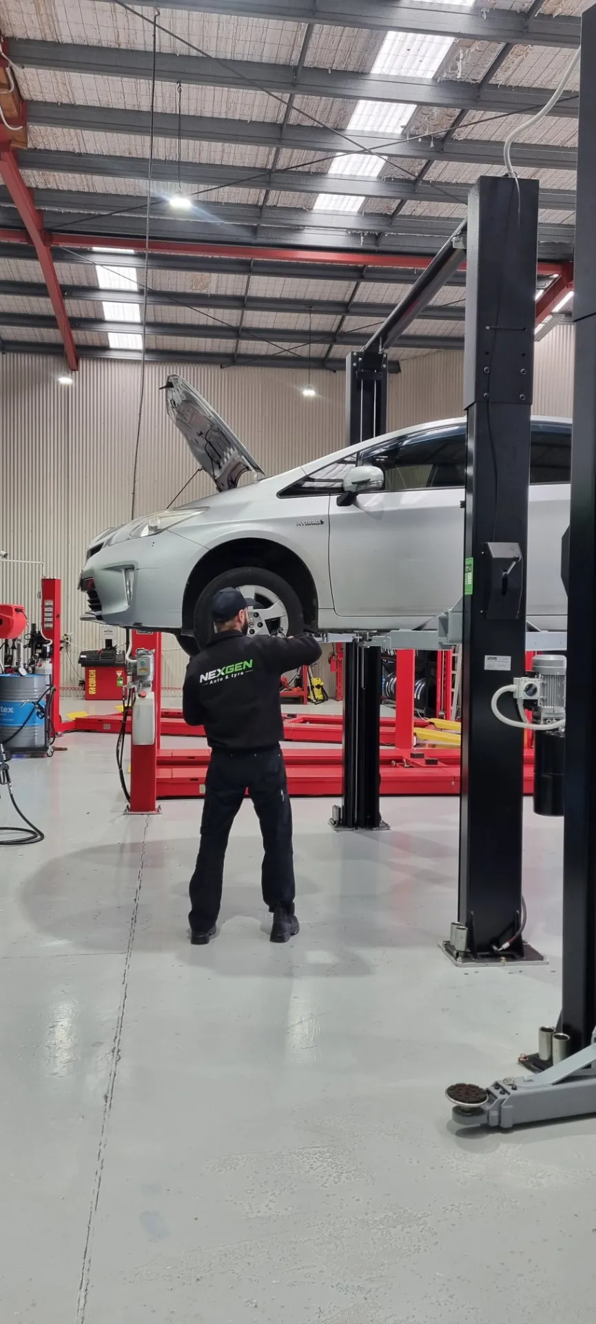 NexGen technician working on a hybrid Prius on the hoist