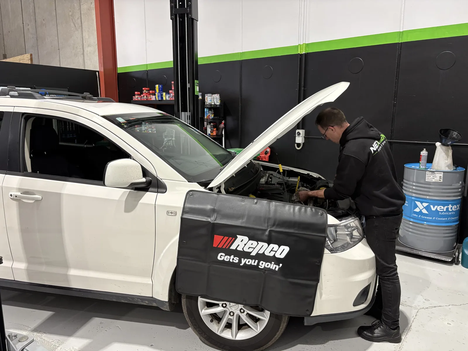 White SUV in the service bay with bonnet up for engine work