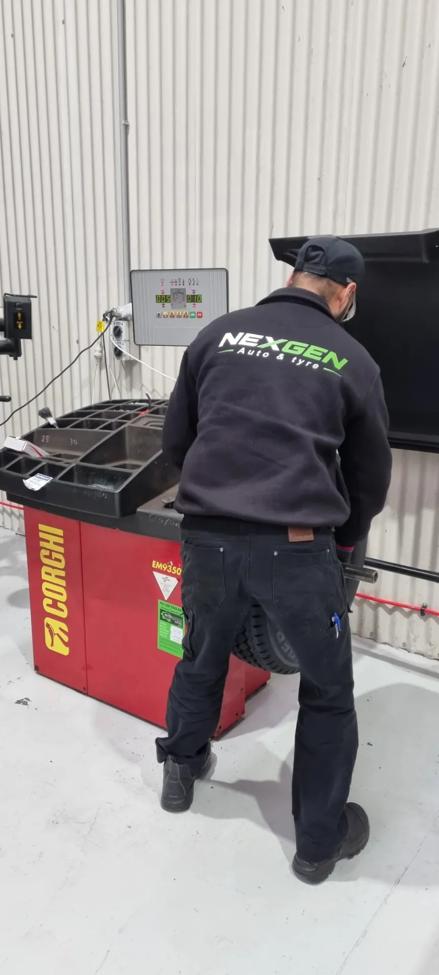 Technician operating the Corghi EM9350 wheel balancer