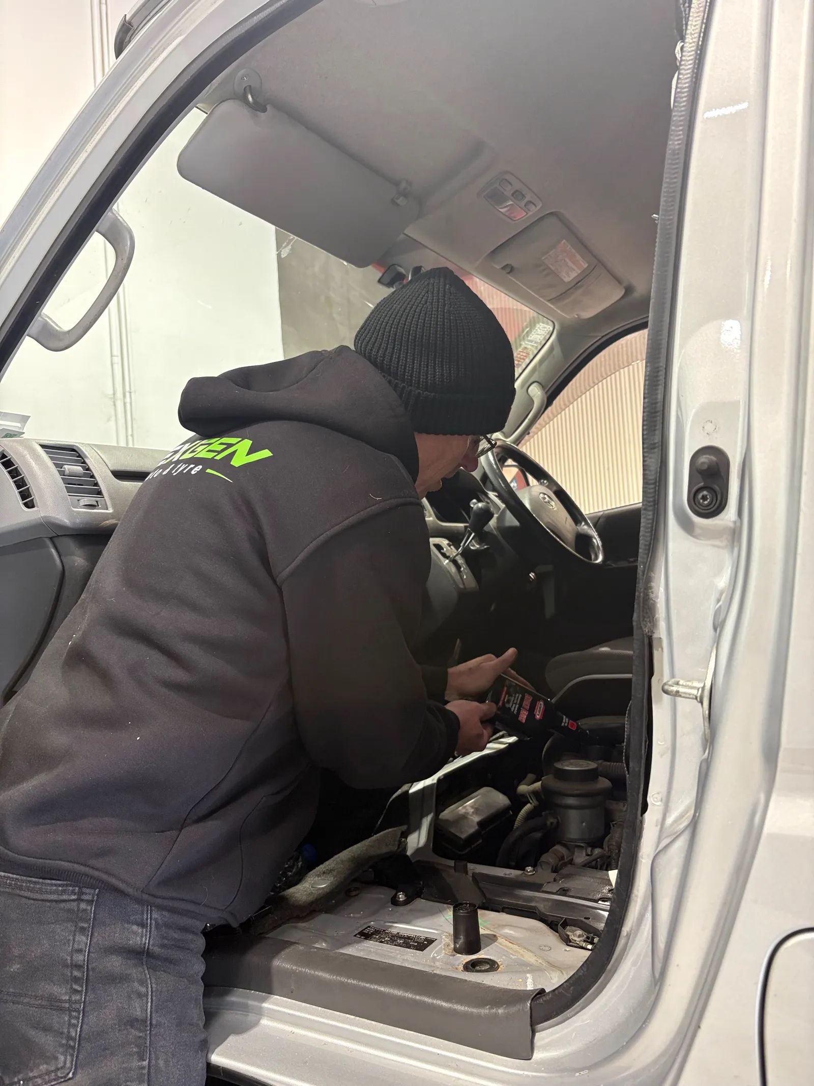 Technician diagnosing the engine bay of a Toyota van